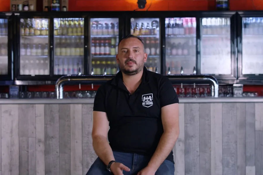 Alexis, franchisé My Beers, devant les réfrigérateurs de son bar