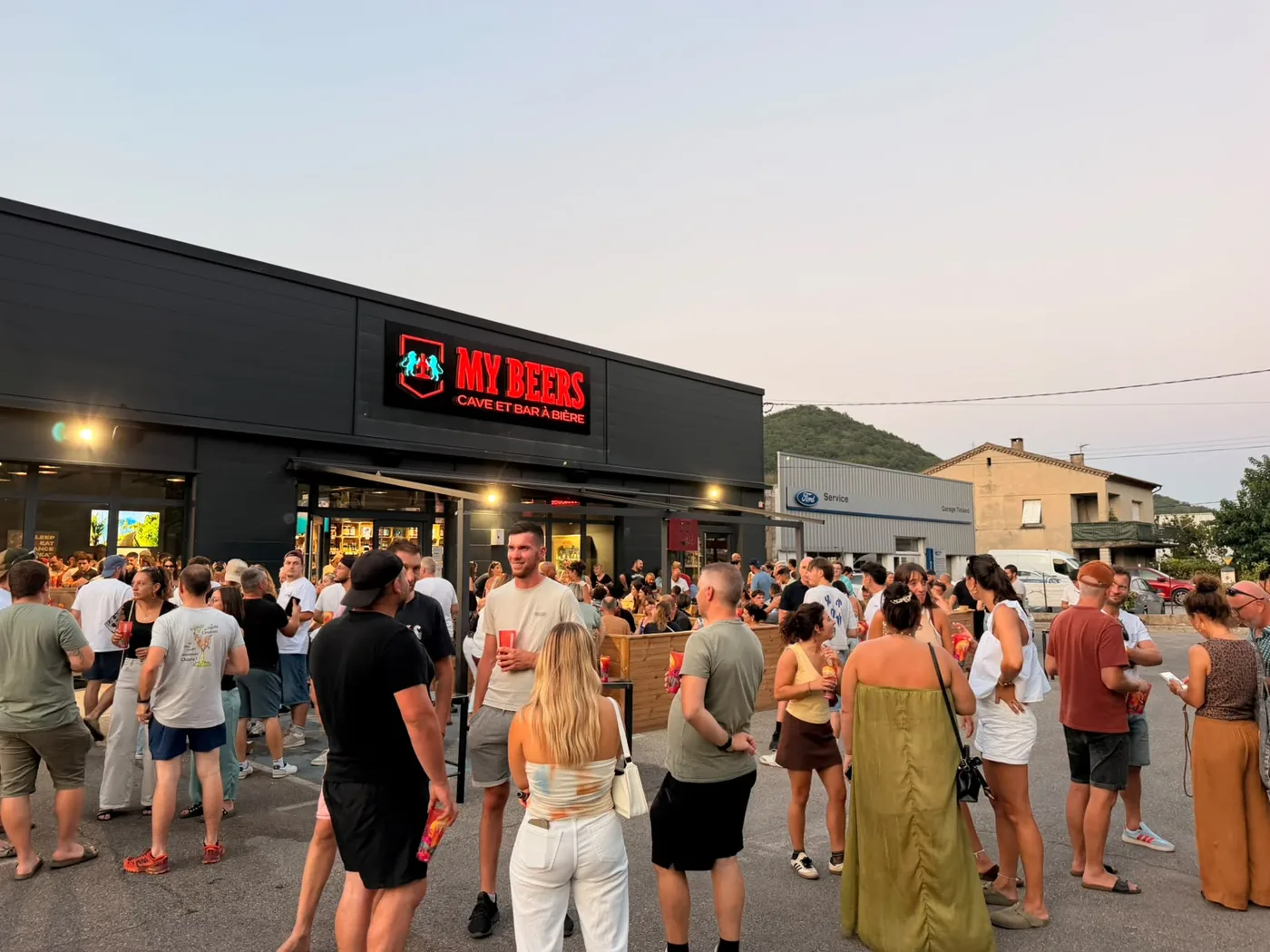Foule devant un bar My Beers au coucher du soleil, le soir de l'ouverture
